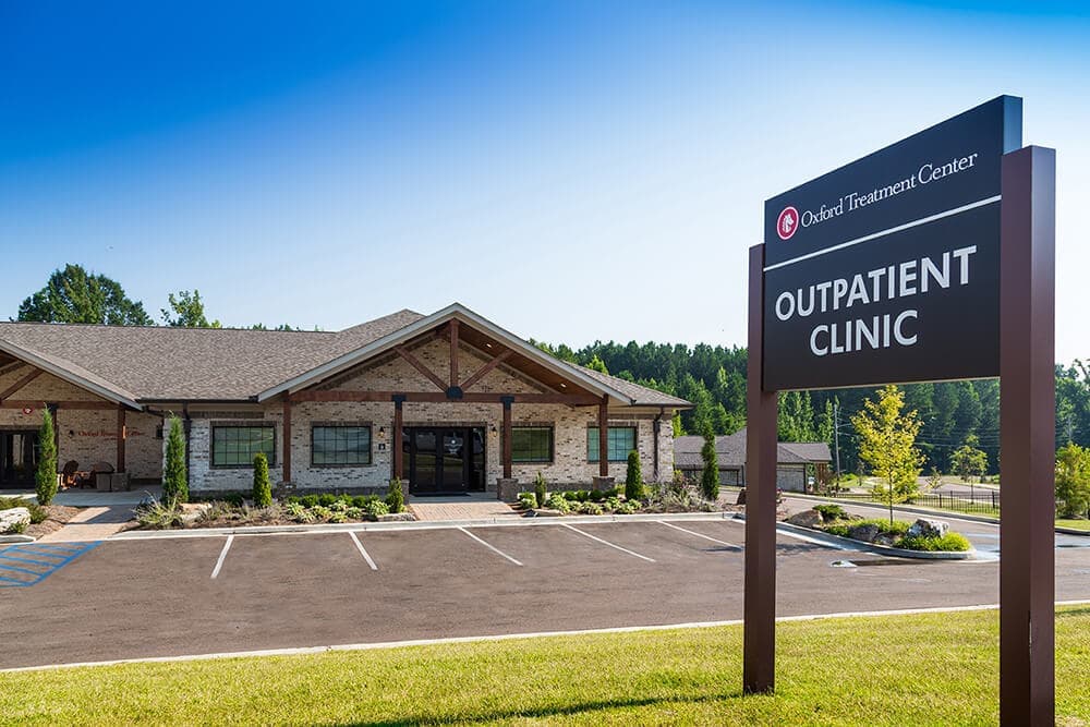 outpatient clinic sign in front of building and parking lot