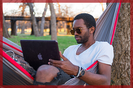 man in hammock on a computer