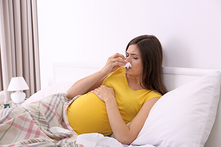 pregnant woman with a cold laying in bed