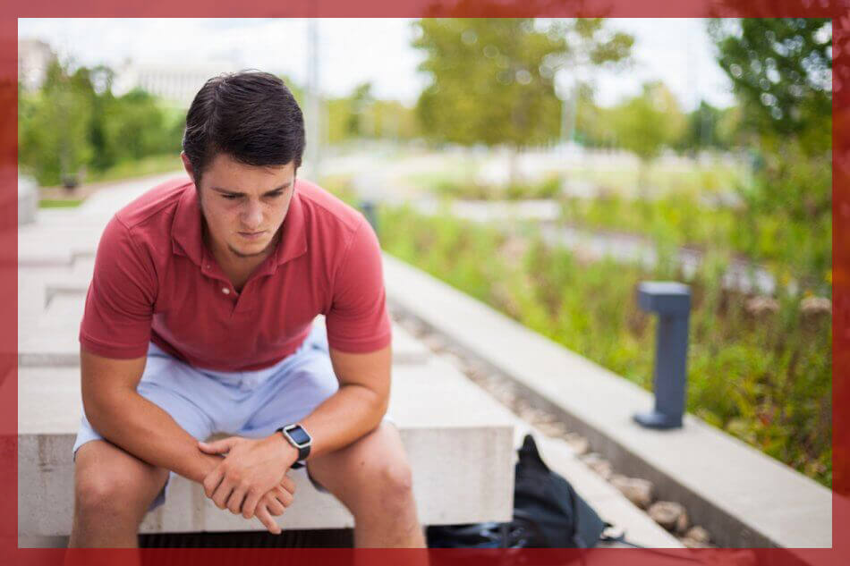 man looking sad at floor sitting down