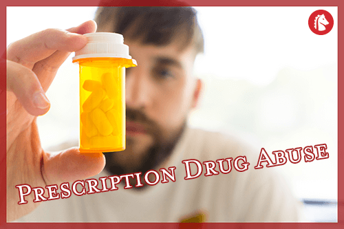 man holding and staring at a bottle of prescription pills