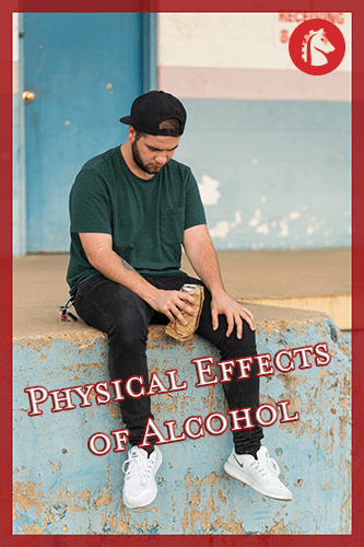man sitting on ledge with alcohol in hand