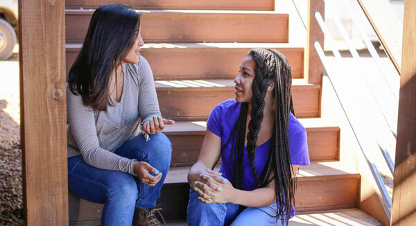 two women sitting on stairs having a conversation